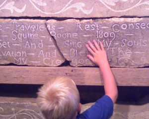 Jake touching a stone carved over 100 years ago at Squire Boon