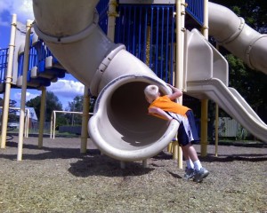 Spencer looking up the slide at the park.